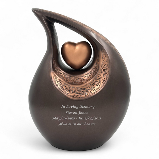 Graceful Urns bronze teardrop cremation urn with floral engraving, heart centerpiece, and personalized memorial text.